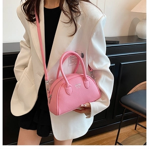 Close-up of pink shell bag with vertical texture and metal logo worn by a model