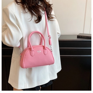Close-up of pink shell bag with vertical embossed texture and adjustable shoulder strap