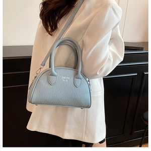 Detail of light blue shell bag with pleated texture and silver hardware on a model