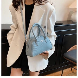 Close-up of light blue pleated shell bag featuring silver zippers and adjustable shoulder strap