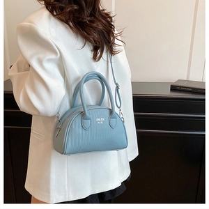 Close-up of light blue shell bag with textured synthetic leather and silver brand text