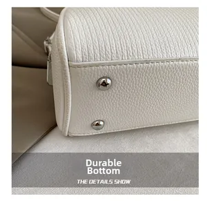 Macro detail of white pebble leather shell bag base with silver anti-wear metal studs