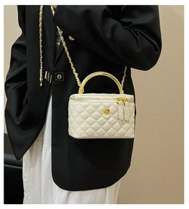 Close-up of quilted cream box bag with gold camellia clasp and chain strap