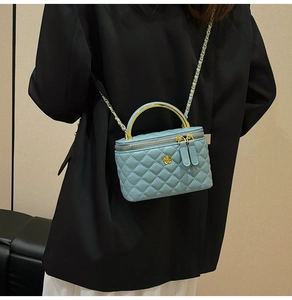 Blue quilted mini box bag with gold floral clasp and chain strap on black blazer