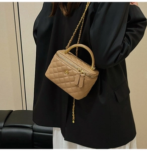 Macro shot of khaki quilted vanity bag featuring gold hardware and chain strap detail