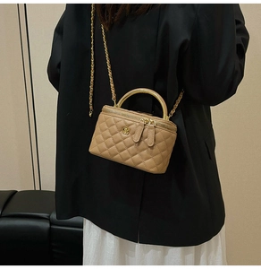 Detail of khaki quilted crossbody bag with gold floral clasp and chain strap