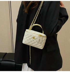 Detail of white quilted handbag featuring gold camellia hardware and chain strap