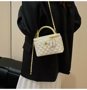 Detailed side view of a white quilted crossbody bag with golden chain and handle
