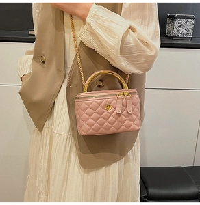 Detailed view of pink quilted leather box bag with gold metal handle and chain strap