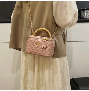 Detail of quilted pink leather handbag with a gold U-shaped handle and metal flower logo