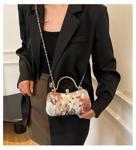 Detail of vintage jacquard evening bag with floral pattern and pearl clasp on suit