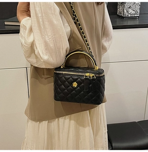 Detail of black quilted chain bag with gold floral clasp and hard metal top handle