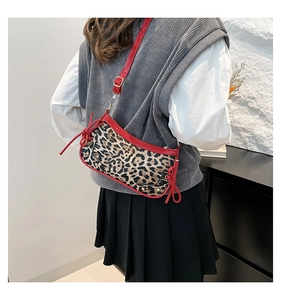 Detail view of stylish leopard print crescent bag with red straps and side bows