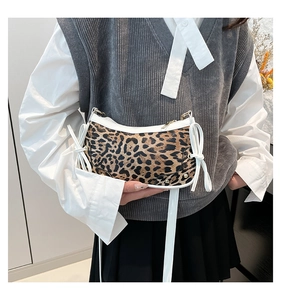 Close-up of leopard print baguette bag with white leather bows and gold zipper detail