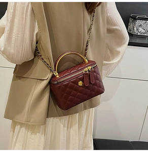 Deep burgundy quilted mini box bag with gold metal handle and leather chain strap shown on model