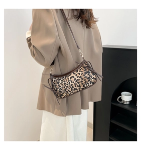 Detail view of leopard print shoulder bag with side bow accents on model