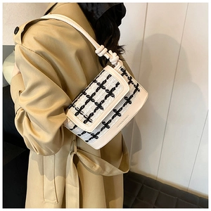 Detail of checkered tweed texture and unique knot shoulder strap on the stylish handbag