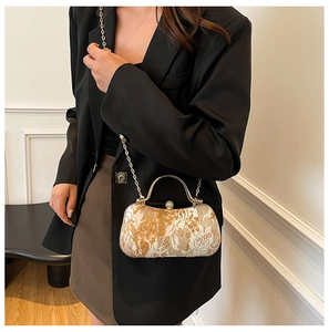 Macro view of gold chain strap and floral embossed pattern on luxury box clutch bag