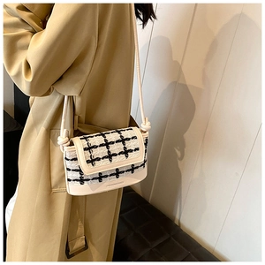Detail of vintage plaid crossbody bag with beige leather trim and slender knot strap