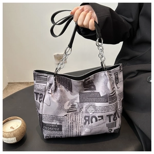 Détail du sac cabas tendance avec imprimé journal et bandoulière en cuir à chaîne argentée