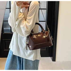 Detail of dark brown leather Boston bag featuring white contrast stitching and gold hardware