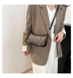 Detailed view of leopard print crossbody bag with black patent leather strap and gold hardware