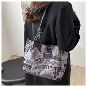 Detailed close-up of newspaper print pattern and silver chain on large tote bag