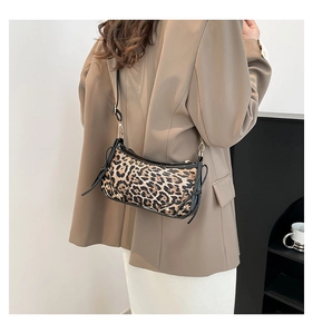 Detail of leopard print underarm bag with black leather trim and gold metal hardware hooks