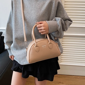 Elegant beige pebbled leather shell handbag with top handle and crossbody strap