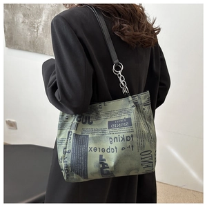 Dettaglio della borsa tote con stampa di giornale, catena metallica e tracolla nera