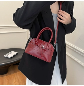 Model wearing a deep red glossy shell bag with stylish belt decor and crossbody strap