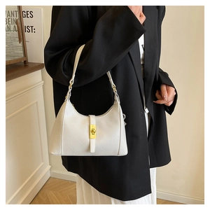 Close-up of a white textured underarm bag featuring a golden metallic twist lock buckle