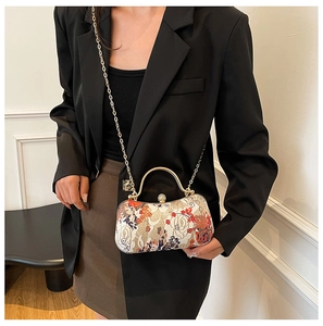 Detail of floral vintage box bag with gold handle and chain on elegant outfit