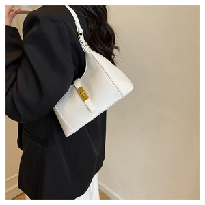 Detail of white embossed leather hobo bag featuring a gold metal twist lock buckle