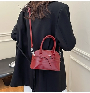 Detailed view of the dark red shell bag with decorative strap and knot detail