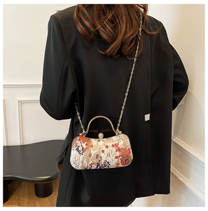 Detail view of floral evening bag with golden circular handle and pearl clasp detail