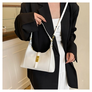Detail of white leather shoulder bag featuring vintage gold piston lock and textured finish