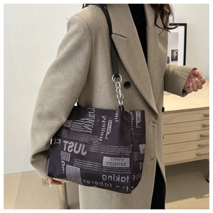 Close-up of newspaper print tote bag featuring black chain straps and grey vintage pattern
