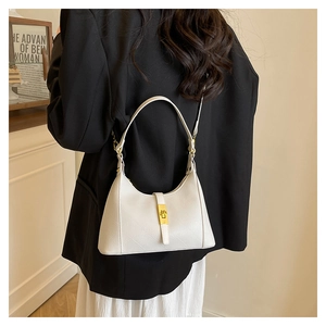 Detail of white dumpling bag showing litchi leather texture and golden twist lock closure