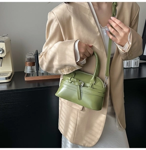 Close-up of avocado green leather crossbody bag with belt buckle detail on a fashion model