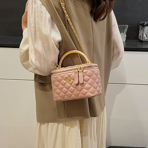 Pink quilted leather box bag with gold handle and chain strap on a fashion model