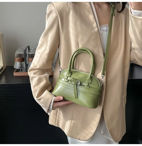 Detail of avocado green shell-shaped crossbody bag with decorative buckle strap