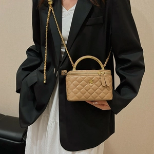 Elegant beige quilted box bag with golden metal handle and chain strap on a model
