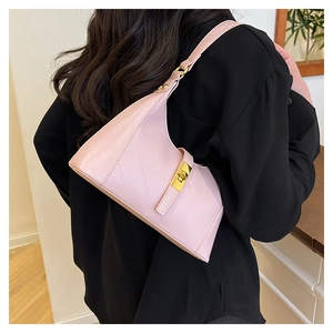 Detail of pink geometric textured hobo bag with gold twist lock on a model's shoulder