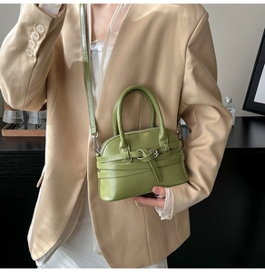 Close-up of grass green shell handbag with glossy finish and decorative belt metal buckle
