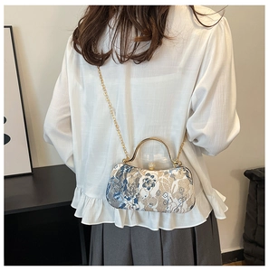 Detail of vintage floral evening bag with golden metal handle and pearl clasp on model