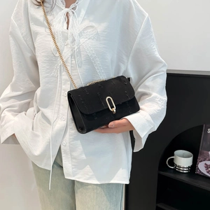 Minimalist black textured fabric crossbody bag with gold chain strap and metal buckle