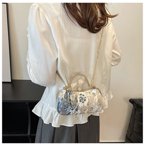 Detailed shot of vintage floral brocade clutch with golden handle and pearl clasp