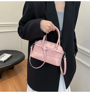 Pink shell handbag with belt buckle detail and adjustable strap shown on model