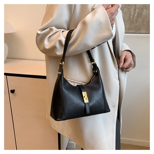 Detailed view of black textured leather bag with elegant gold twist-lock closure